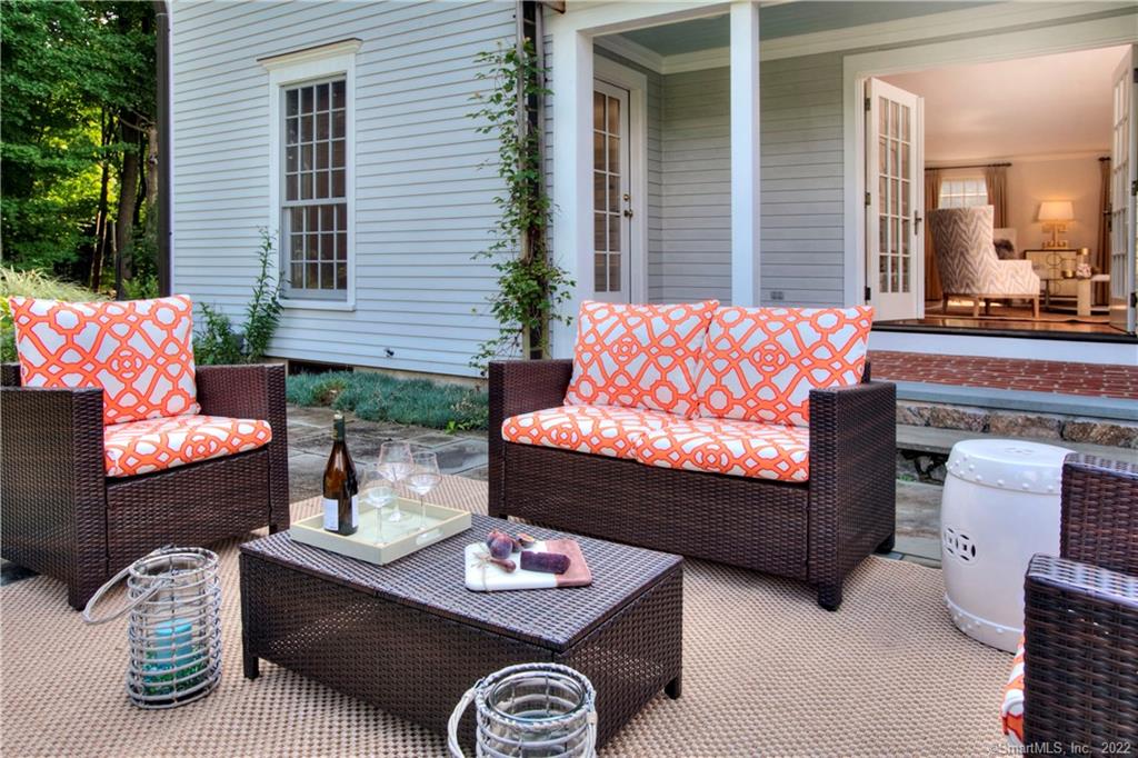 Wicker outdoor seating set with orange patterned cushions on a neutral area rug.